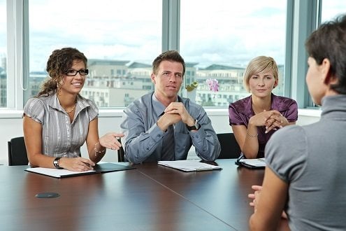 Panel of business people sitting at table in meeting room conduc