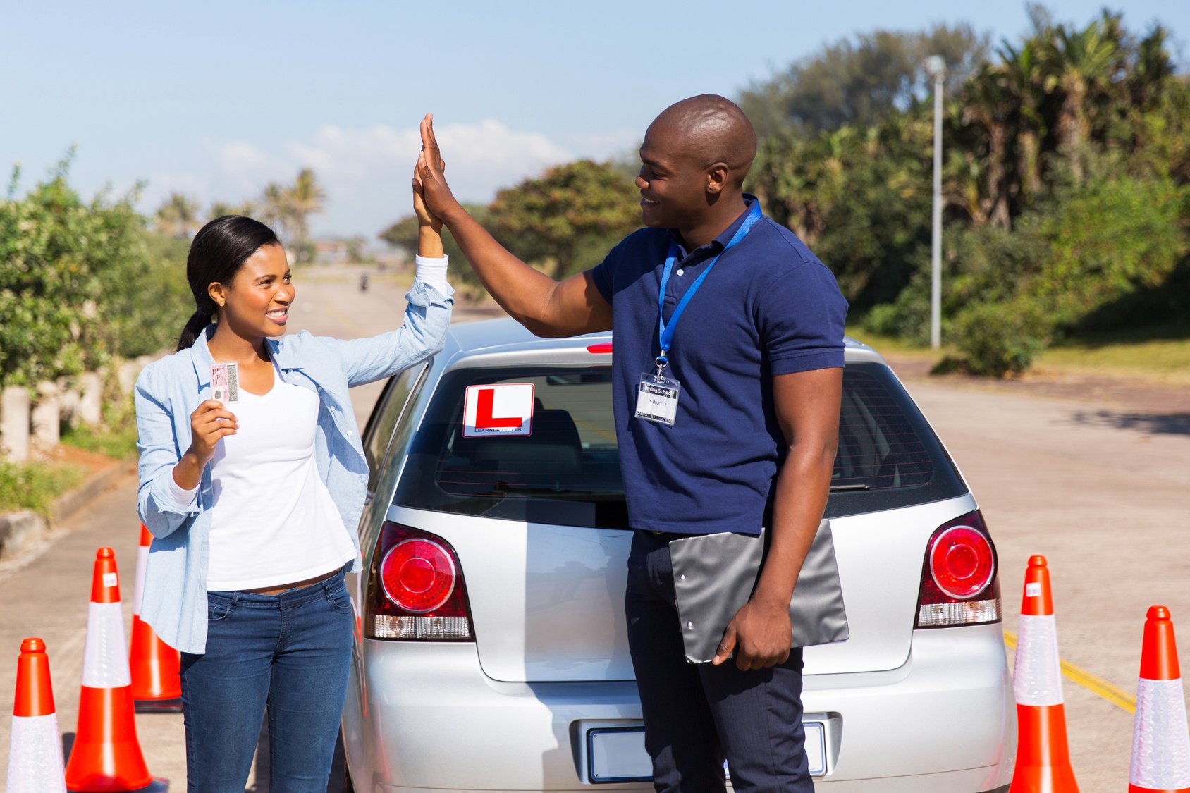 happy african girl and driving instructor doing high five after getting her driving license
